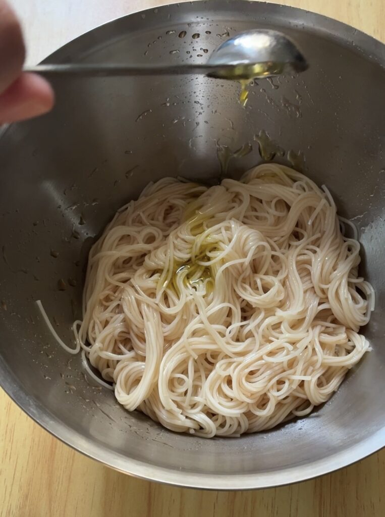 うどんタレで和えたそうめんにオリーブ油を入れている画像