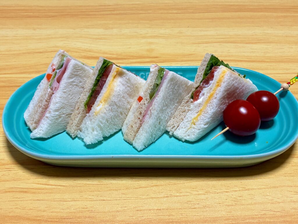 ル・クルーゼロングオブプレートにサンドイッチとミニトマトを乗せた画像